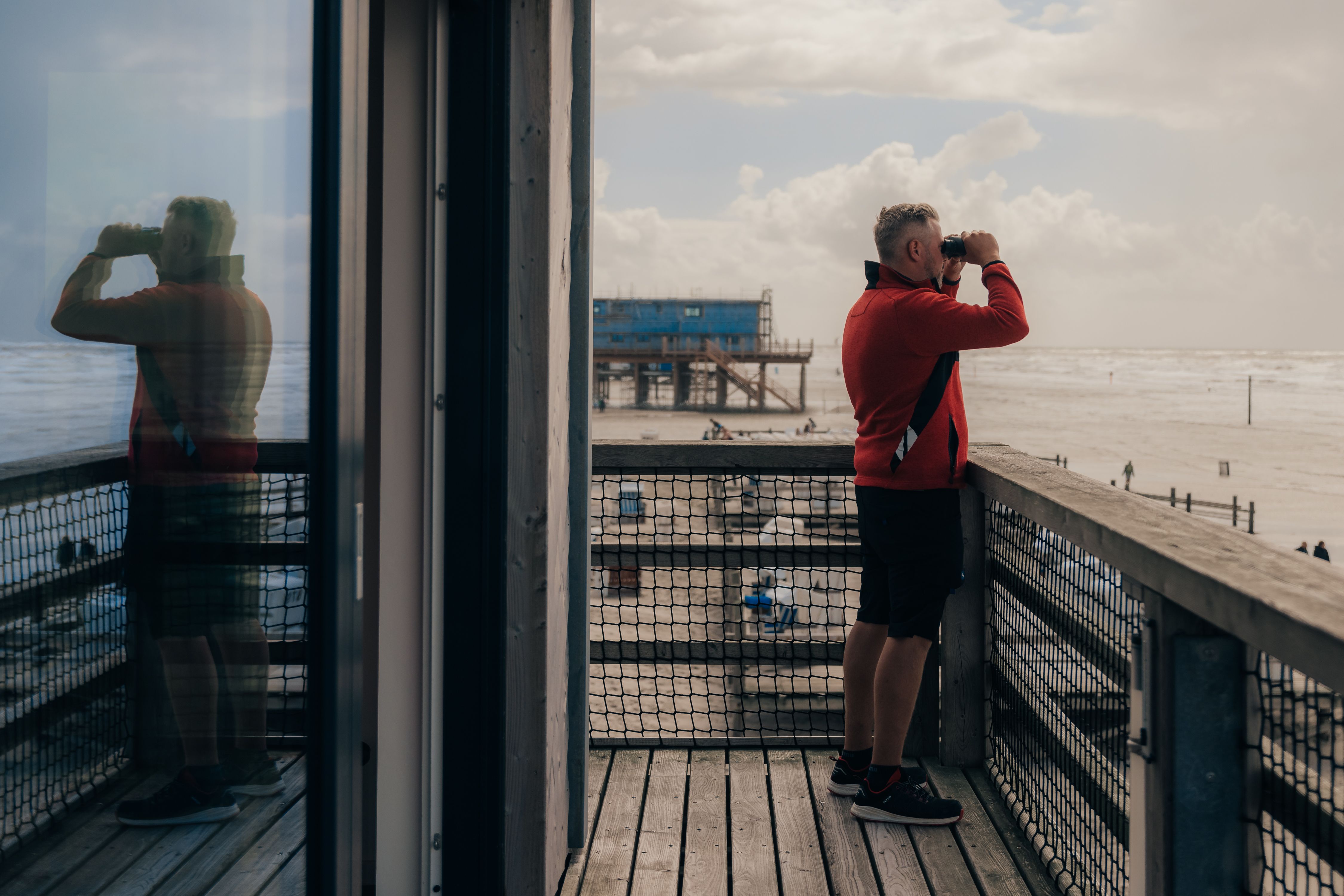 Dennis - Mitarbeiter der Strandrettung St. Peter-Ording - bei seiner Arbeit. Mit seinem Fernglas hat er von hoch oben auf dem Pfahlbau den ganzen Strand im Blick.