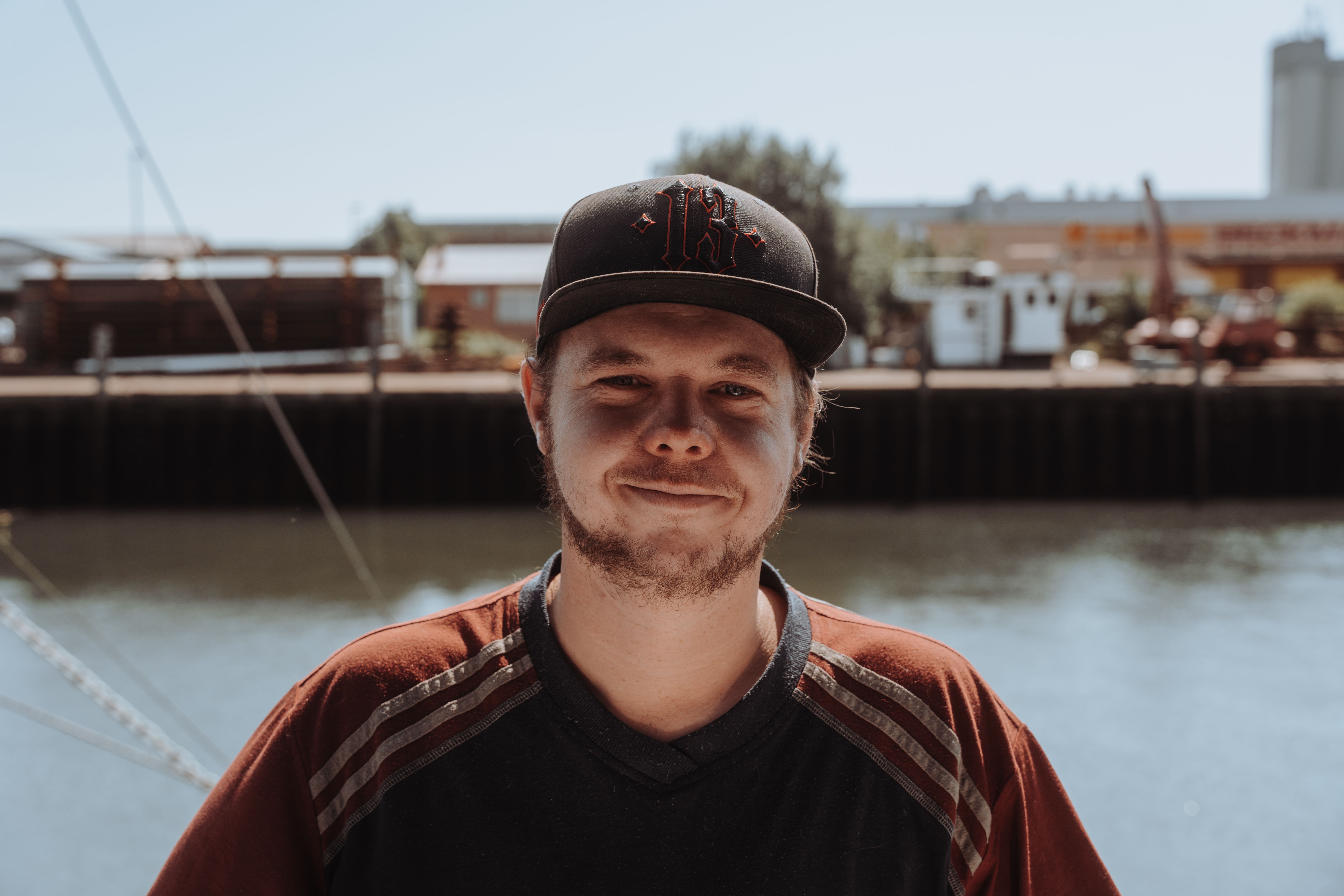 Ein junger Mann mit eine Cappy auf dem Kopf posiert vor dem Hafen von Büsum