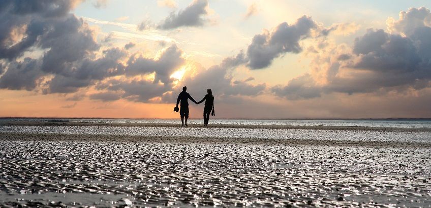 Pärchen bei einem romantischem Abendspaziergang im Watt auf Föhr. Urlaub zu Zweit an der Nordsee genießen.