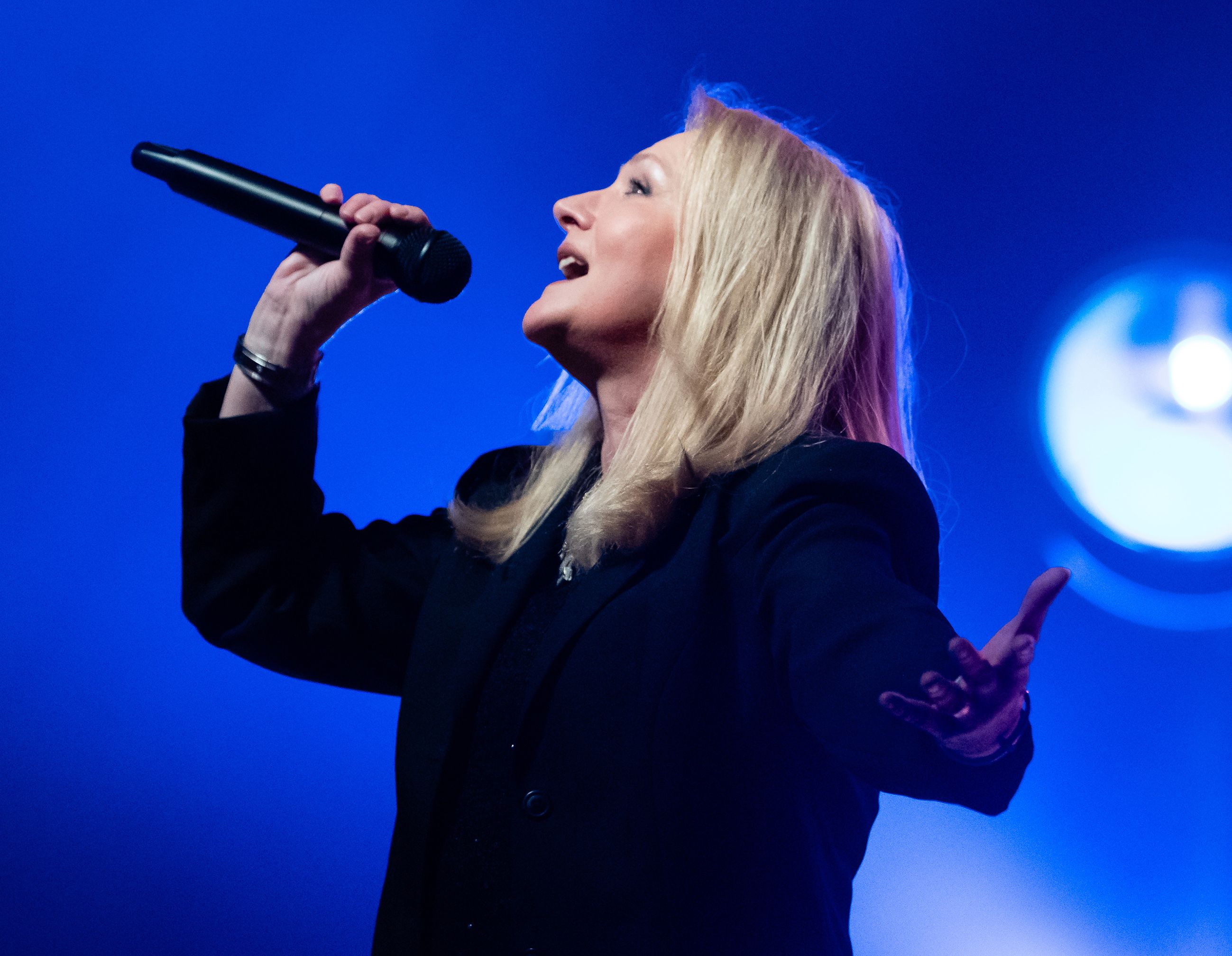 Nicole singt vor einem blauen Hintergrund auf der Bühne