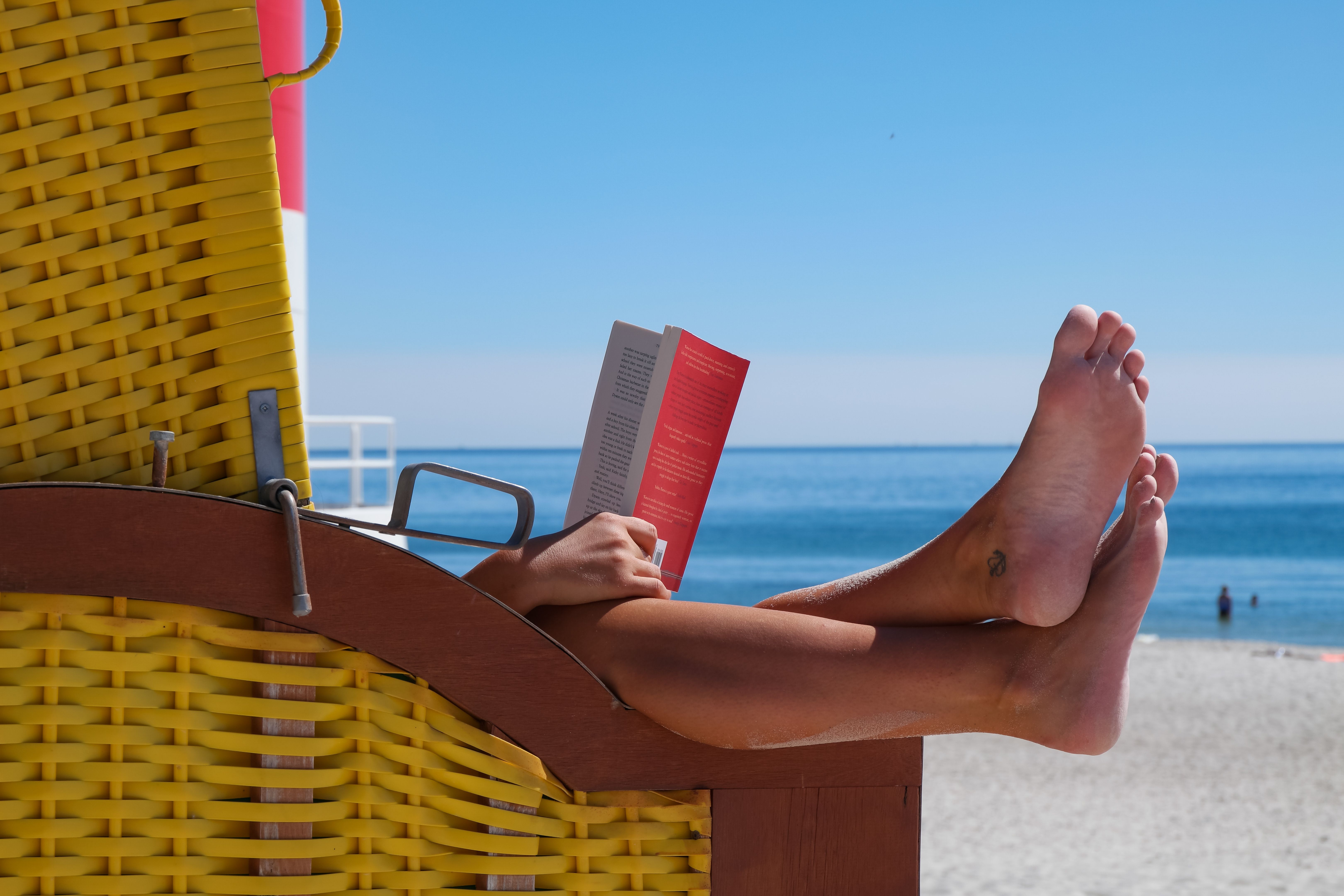 Ein Strandorb steht am Helgoländer Südstrand, in dem jemand ein Buch liest und die Füße heraus hängen lasst