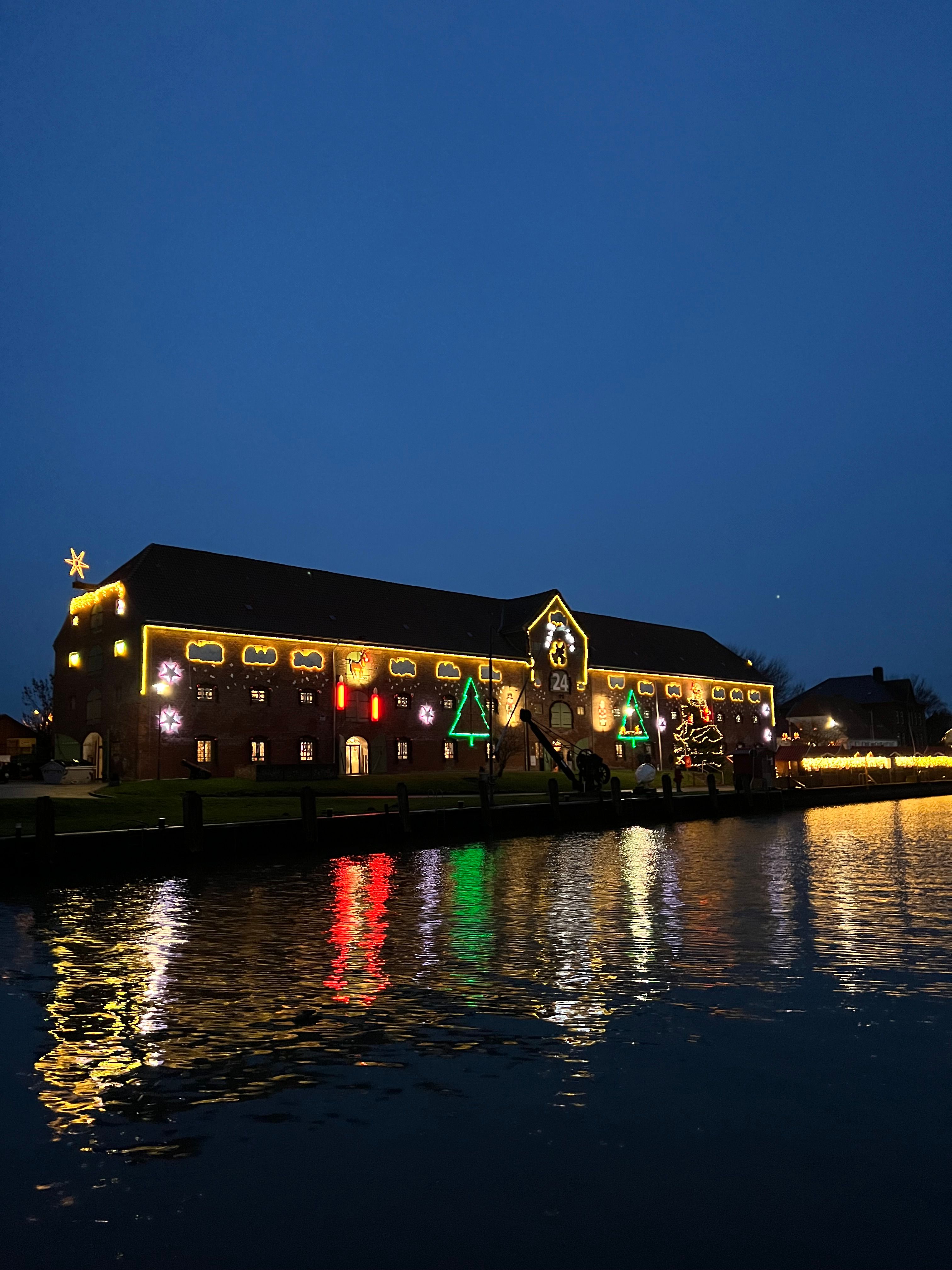 Blick auf das weihnachtliche Packhaus Tönning über Wasser von außen im Dunkeln