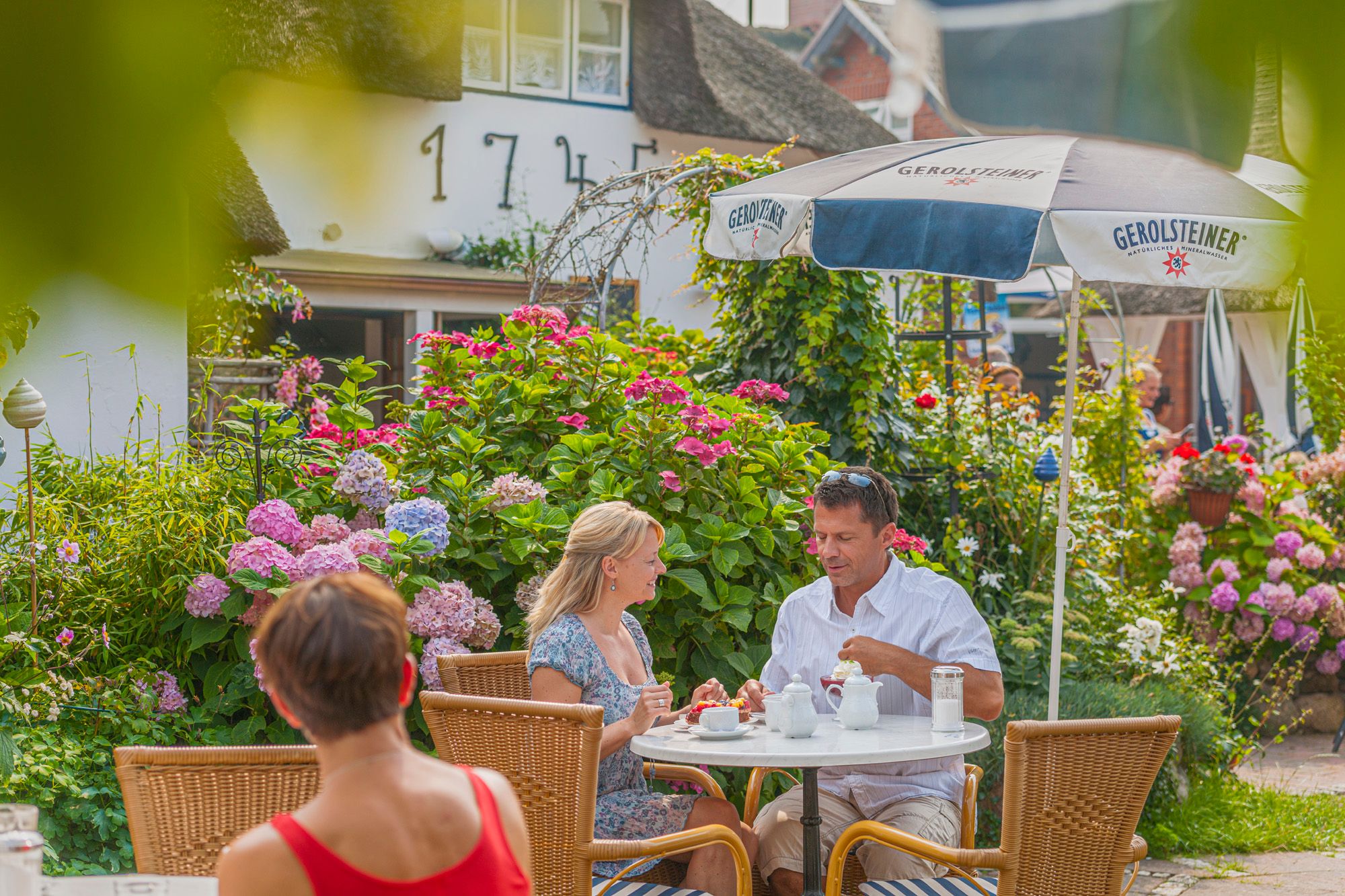 Gäste sitzen auf der Terrasse des Friesen-Cafés und genießen Kaffee und Kuchen