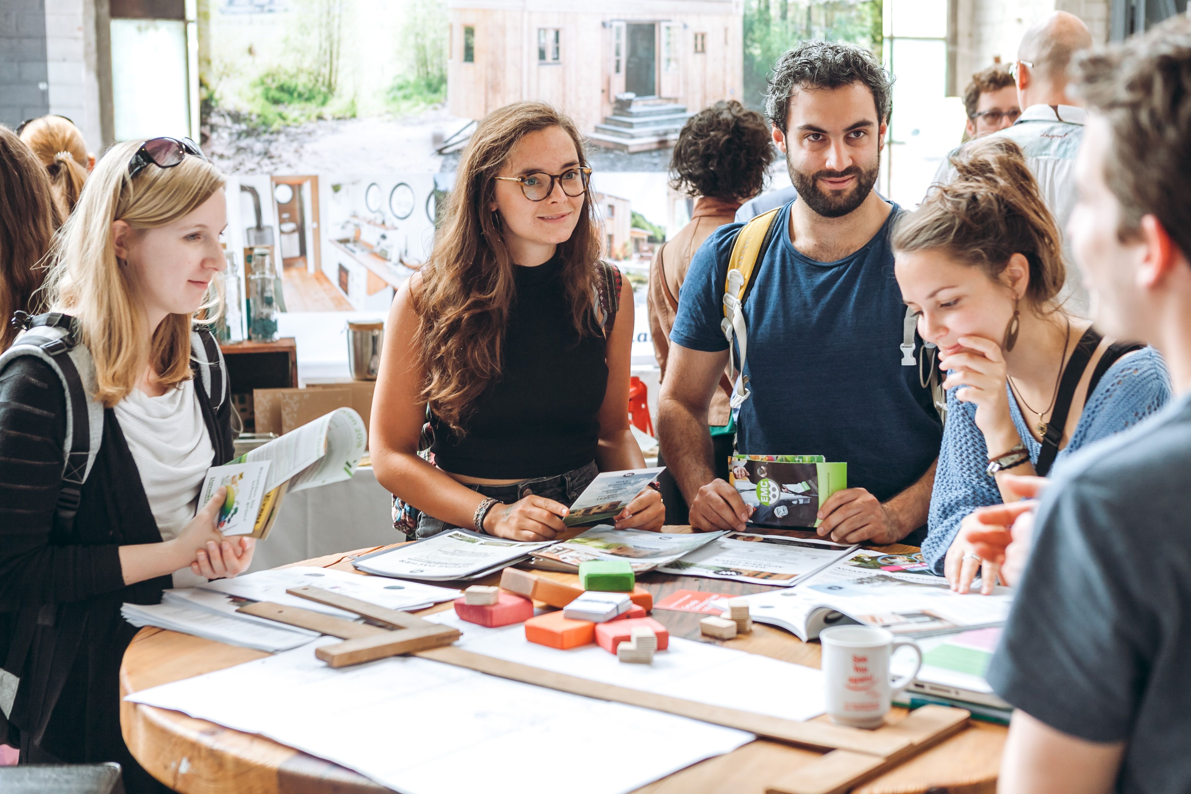 Interessierte Messebesucher informieren sich auf der Green World Tour an einem runden Tisch, auf dem viele Prospekte liegen