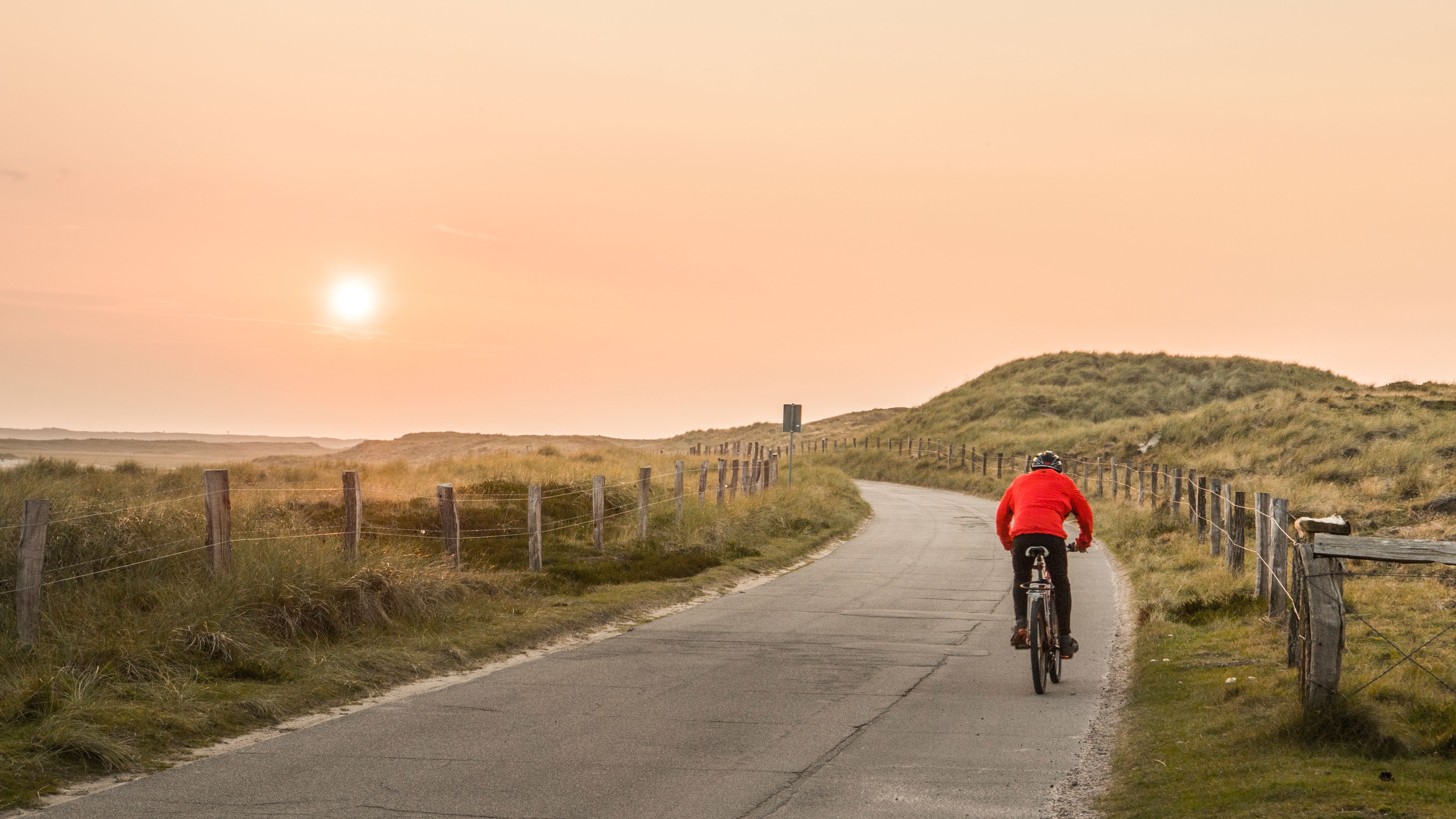 Ein Radfahrer fährt am Lister Ellenbogen dem Sonnenuntergang entgegen