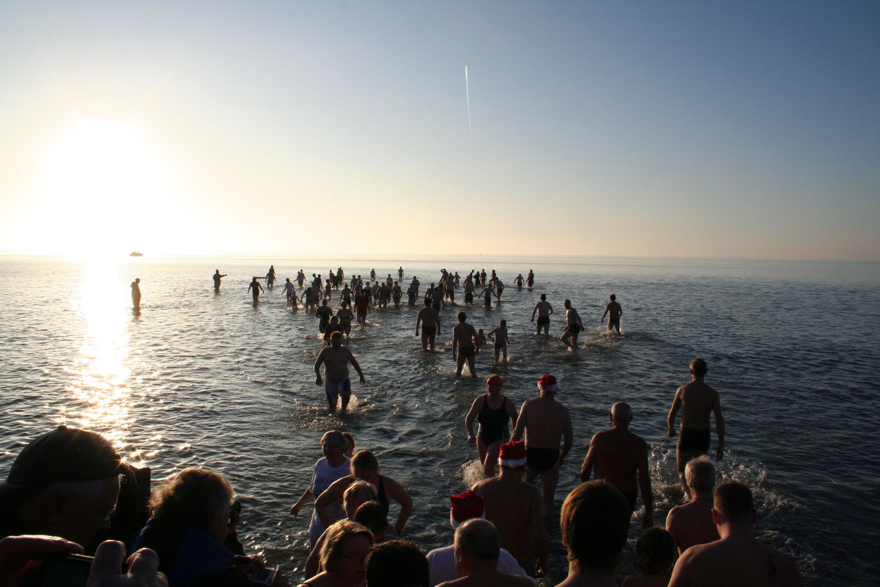 Viele Gäste schwimmen beim Anbaden in der Nordsee vor Büsum, Zuschauer schauen ihnen dabei zu